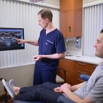 Dr. Howard pointing to x ray with male patient