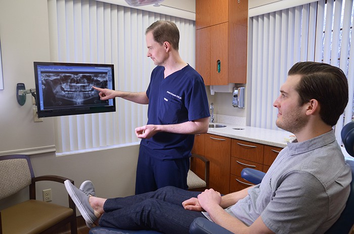 Dr. Howard pointing to x ray with male patient